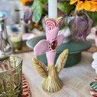 Decorative candle holder shaped like a pink flower with green leaves on a table.