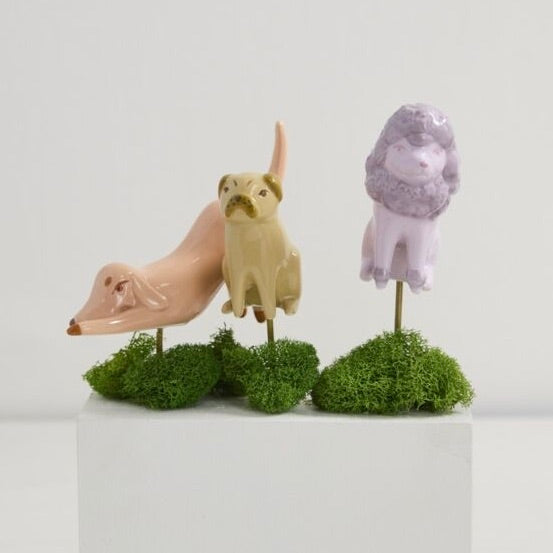 Three animal figurines on green spherical bases against a white background