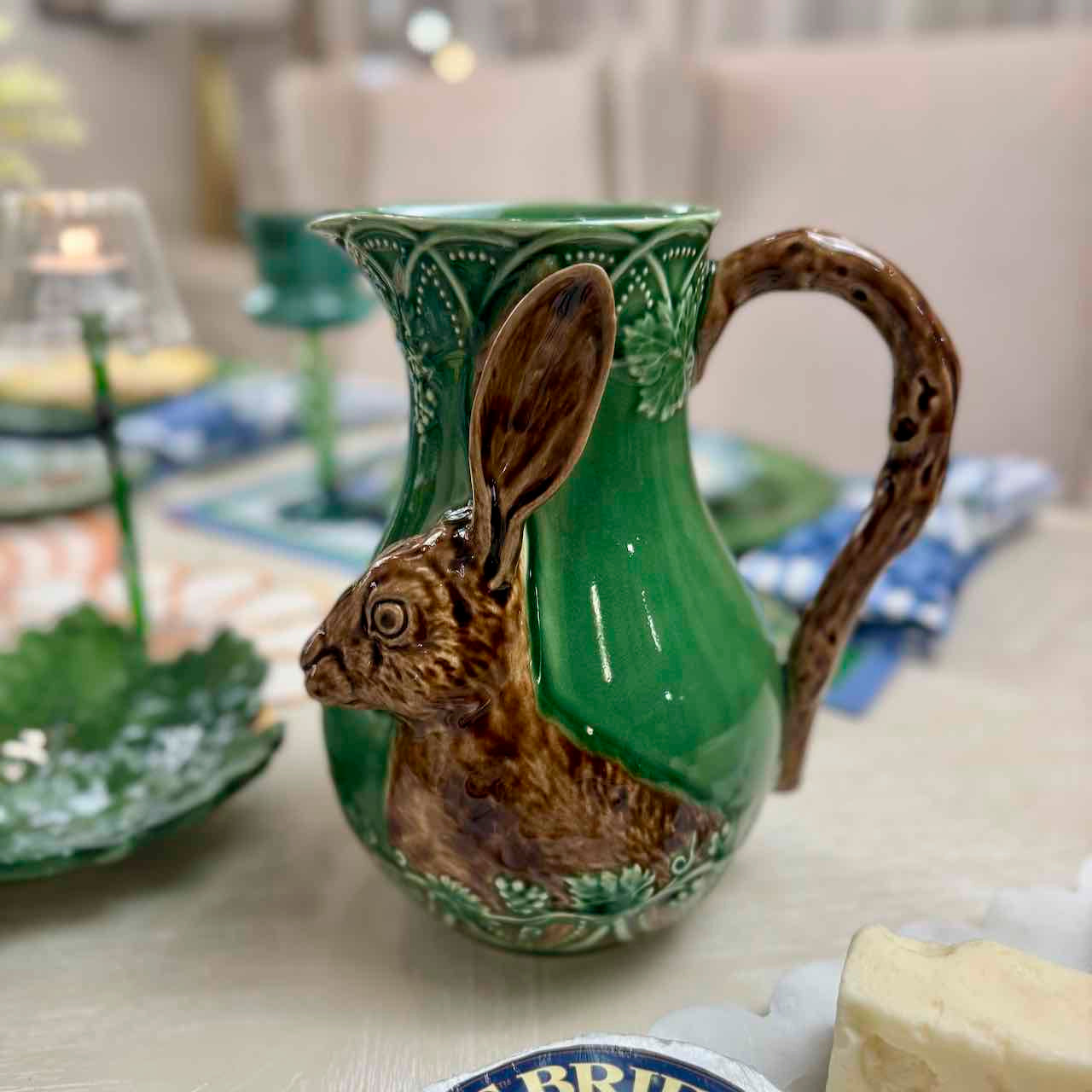 Green ceramic pitcher with a rabbit design on a table.