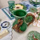 Green ceramic pitcher with rabbit handle on a table setting