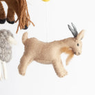 Felted animal toy, specifically a goat, hanging against a white background