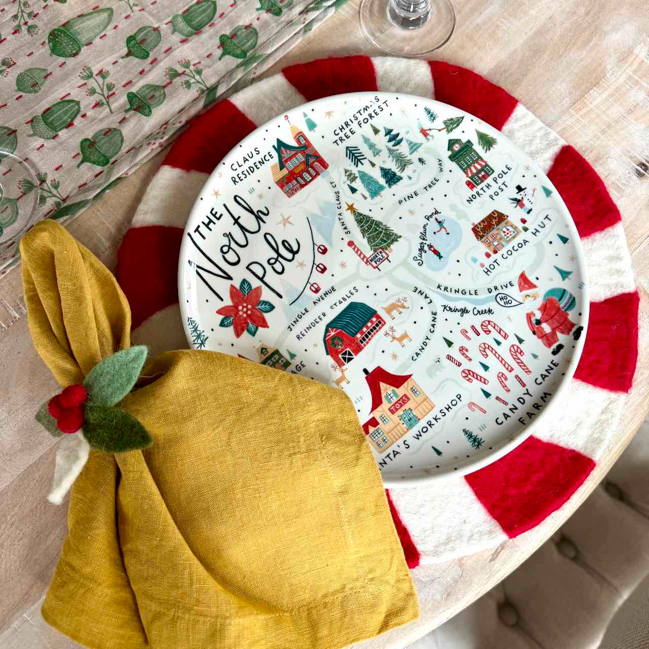 Round plate with Christmas-themed design on a table with a yellow napkin.