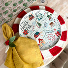 Round plate with Christmas-themed design on a table with a yellow napkin.