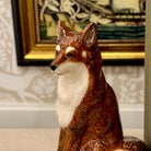 Decorative fox figurine in a room with framed artwork on the wall.