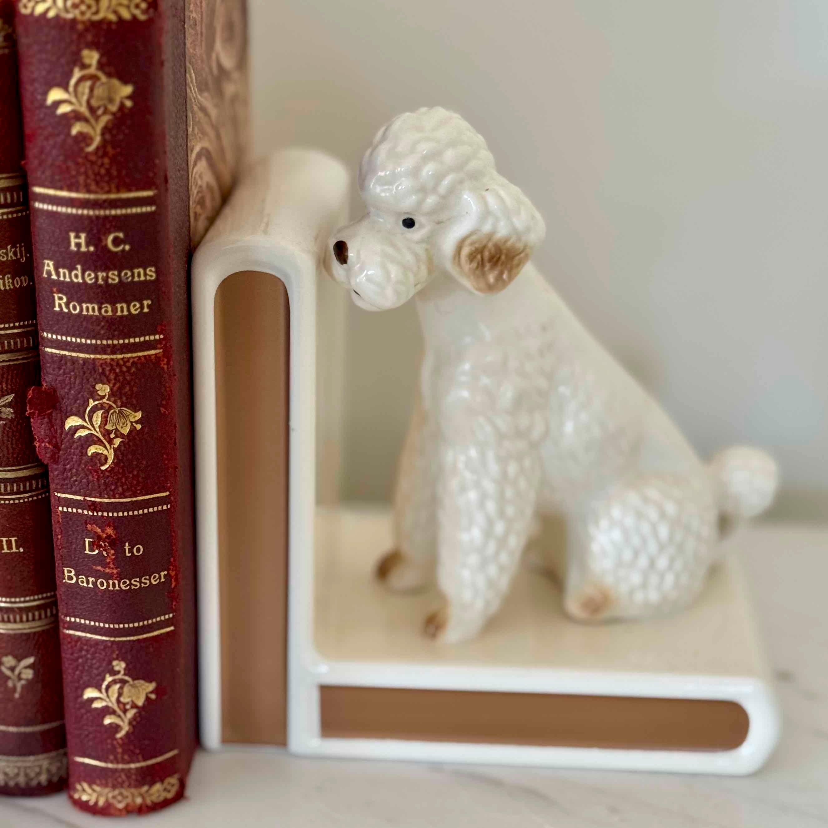 White ceramic poodle figurine on a book with red spines