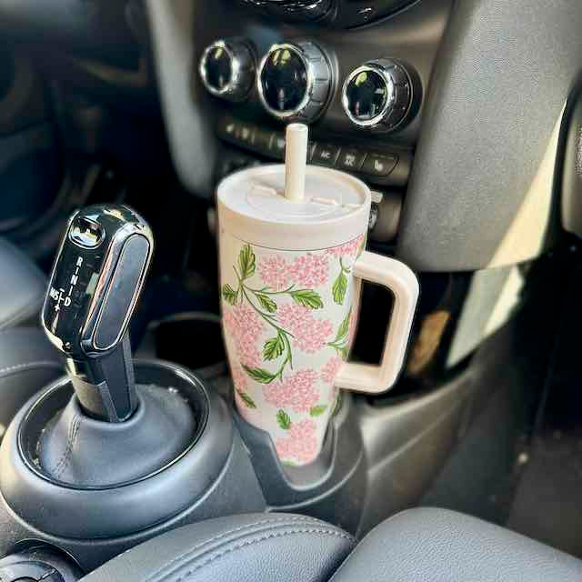 Floral-patterned cup with straw in a car cup holder