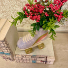 Ceramic shoe with greenery and flowers on top of books