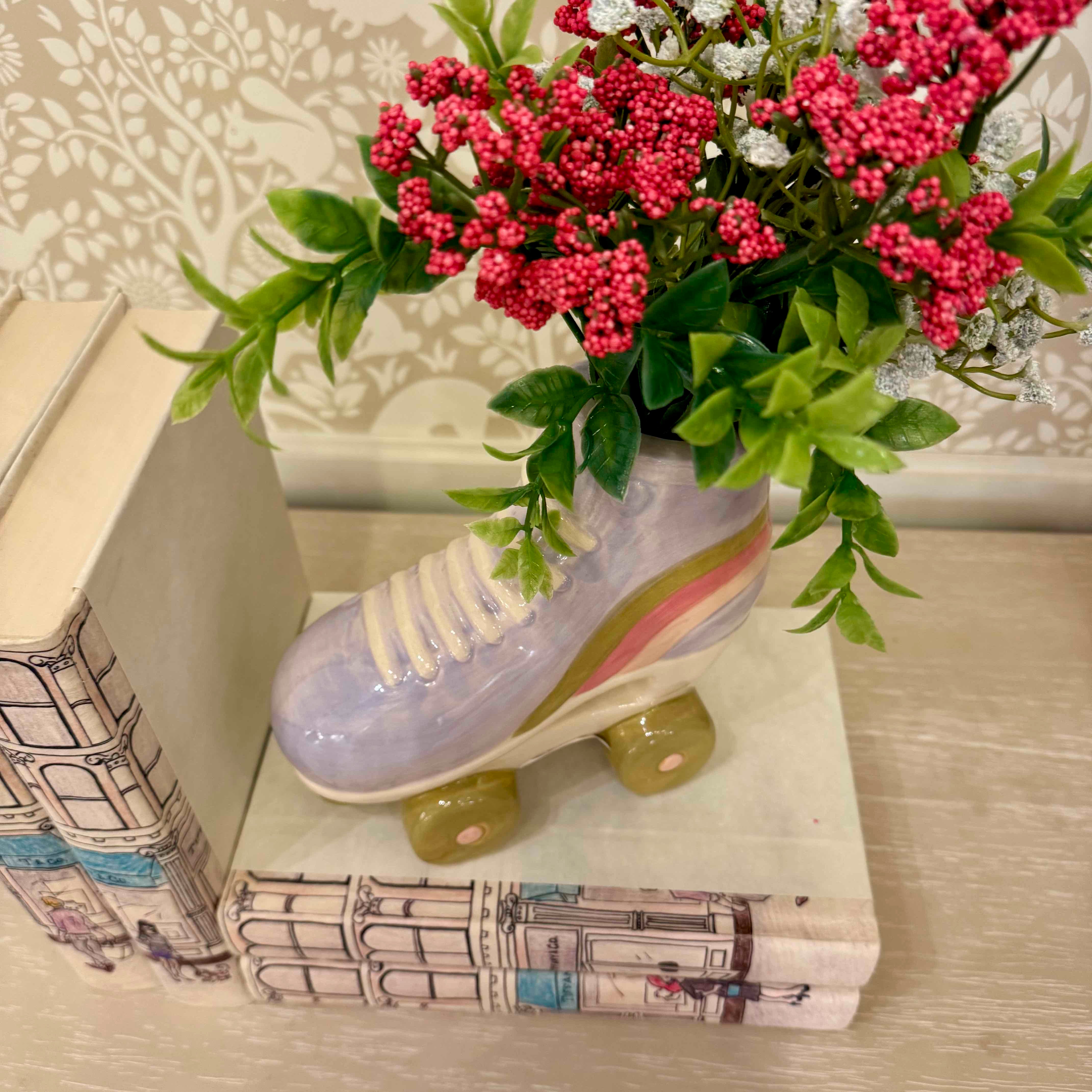 Ceramic shoe with greenery and flowers on top of books