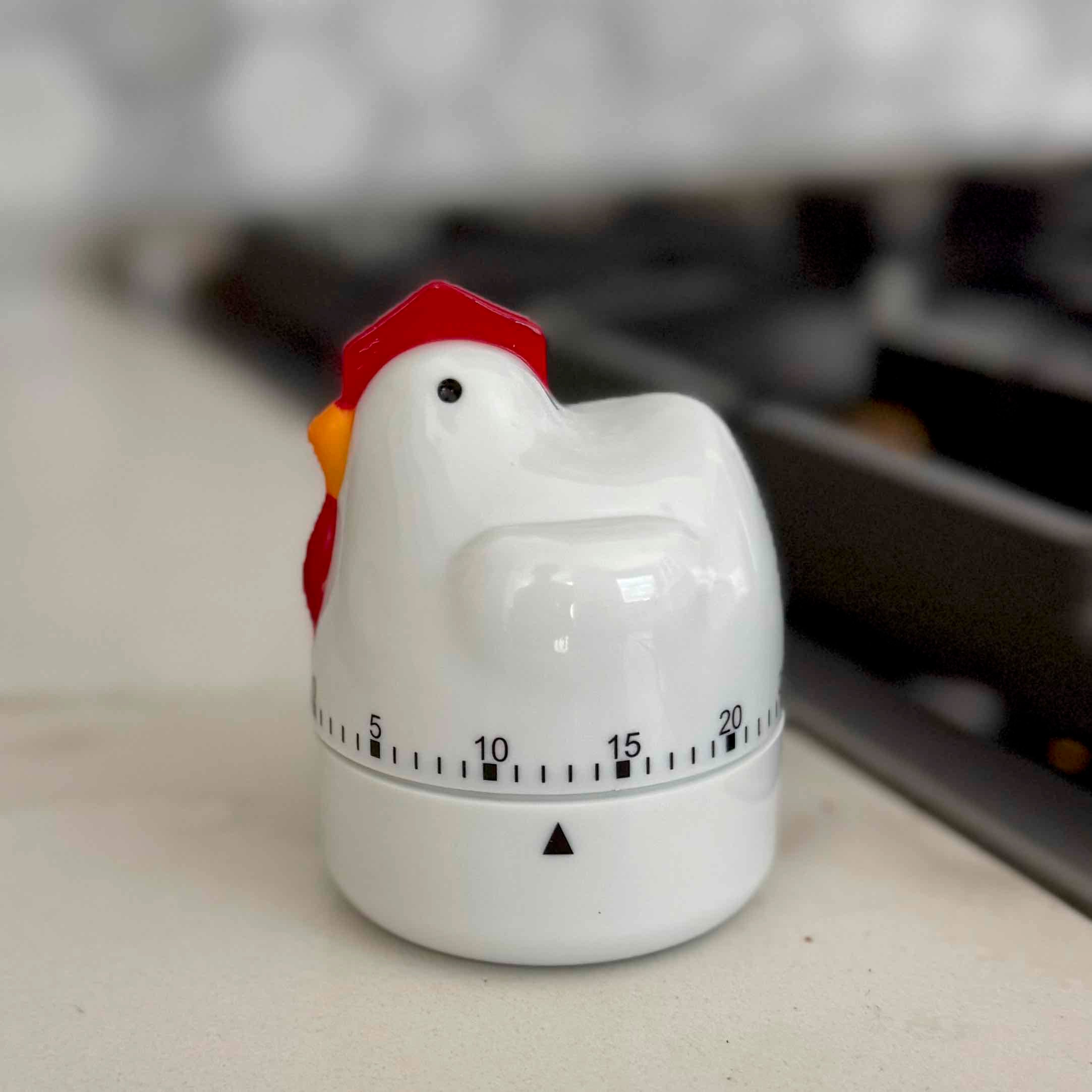 Chicken-shaped kitchen timer on a surface with a blurred background