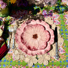 Decorative table setting with floral plates and cutlery on a colorful tablecloth.