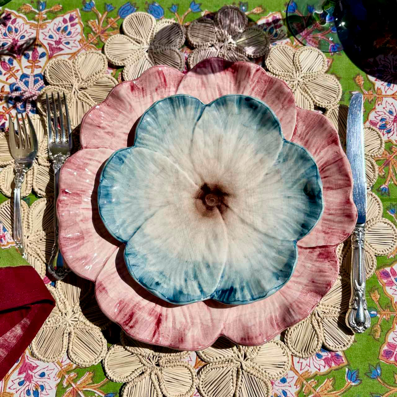 Floral-patterned plates on a decorative tablecloth with cutlery.
