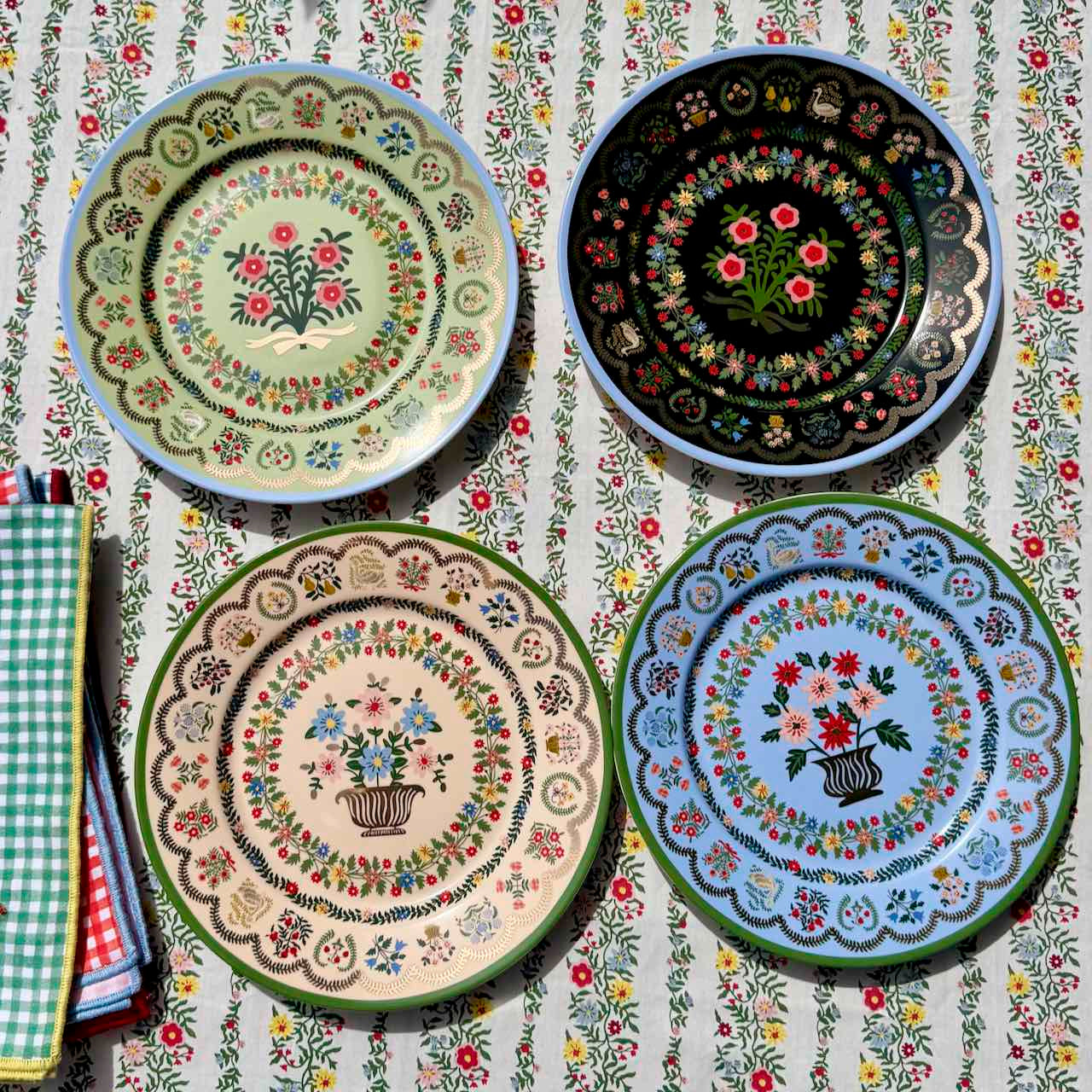 Four decorative plates with floral patterns on a matching tablecloth.