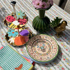 Decorative table setting with floral cookies, a vase of flowers, and a decorative plate on a patterned tablecloth.
