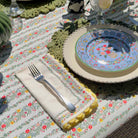 Decorative table setting with floral tablecloth, plates, and cutlery on a patterned surface.