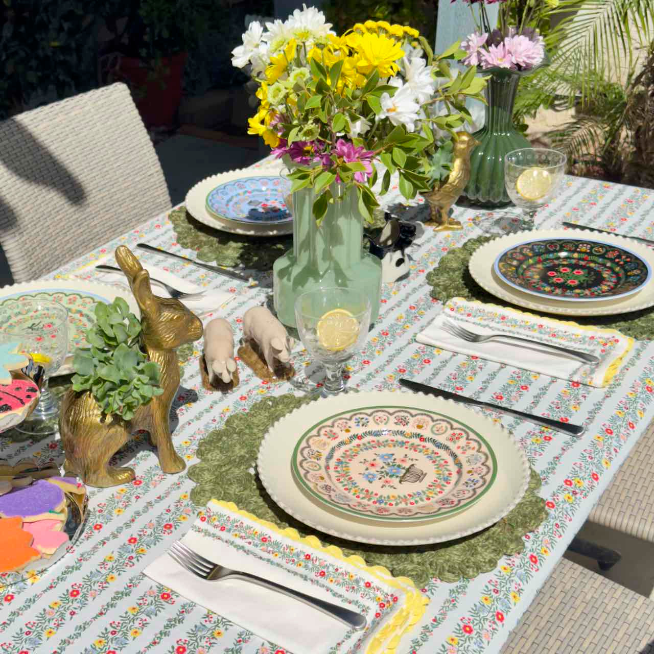 Decorative table setting with floral centerpieces, plates, and cutlery on a patterned tablecloth.