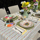 Dining table set with floral tablecloth, plates, cutlery, and decorative items outdoors.