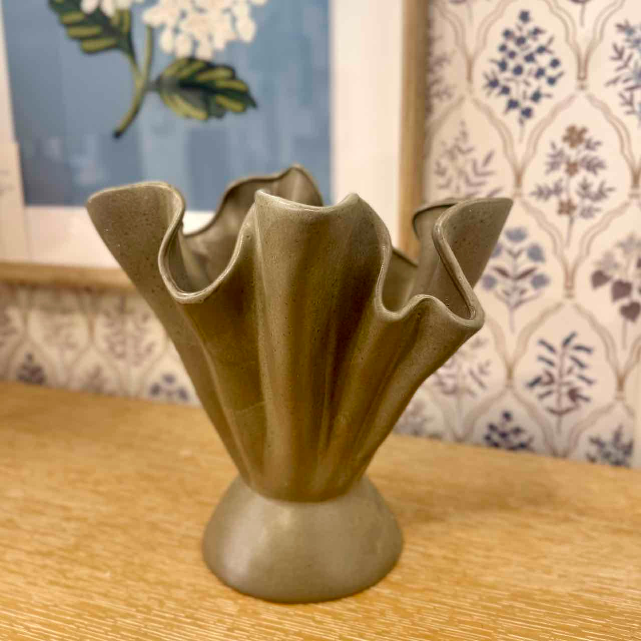 Decorative ceramic vase on a wooden surface with a patterned wall in the background