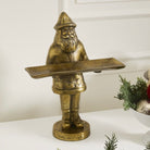 Bronze statue of a gnome holding a tray on a white surface with decorative elements.