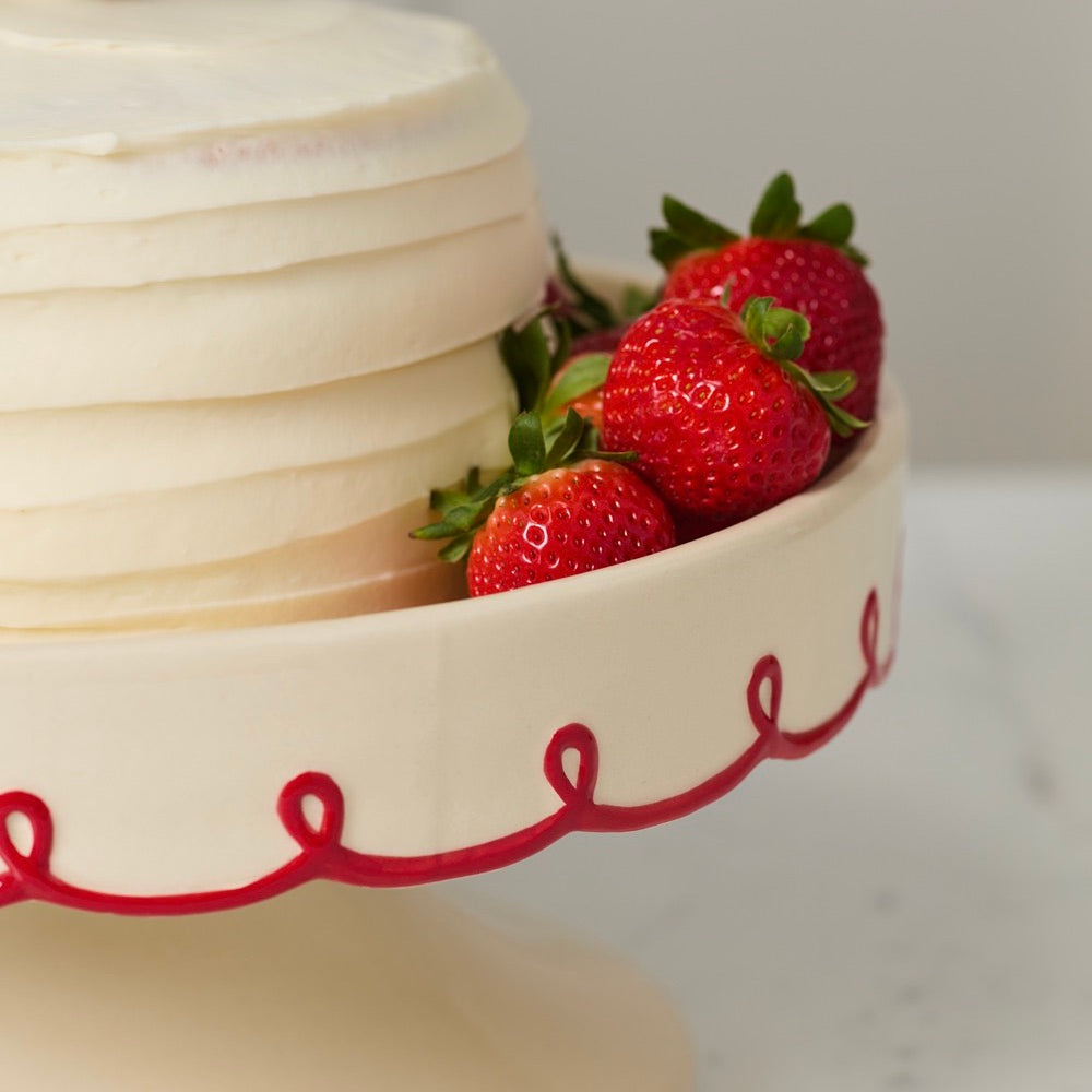 White cake with red decorative text and strawberries on a white background