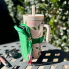 Green leaf-shaped pouch with a floral mug on a metal surface outdoors