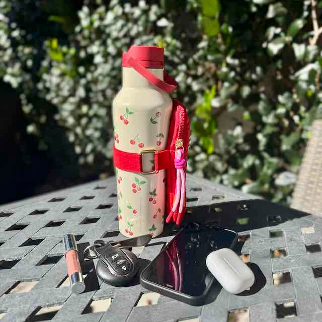 Water bottle with cherry design on a table outdoors