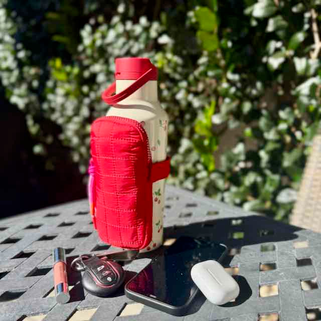 White water bottle with a red holder on a table outdoors