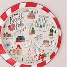 Two decorative plates on a light wooden surface, one with a peppermint swirl pattern and the other with a festive map design.