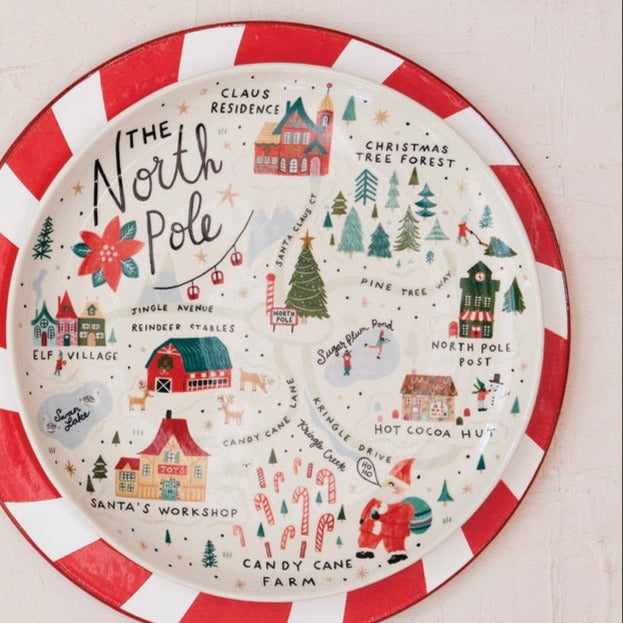 Two decorative plates on a light wooden surface, one with a peppermint swirl pattern and the other with a festive map design.
