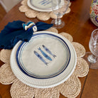 Table setting with a decorative plate featuring fish illustrations on a woven placemat.