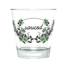 A clear glass tumbler with a printed floral wreath design and the word 'sauced' in black script across the front, shown on a plain white background.
