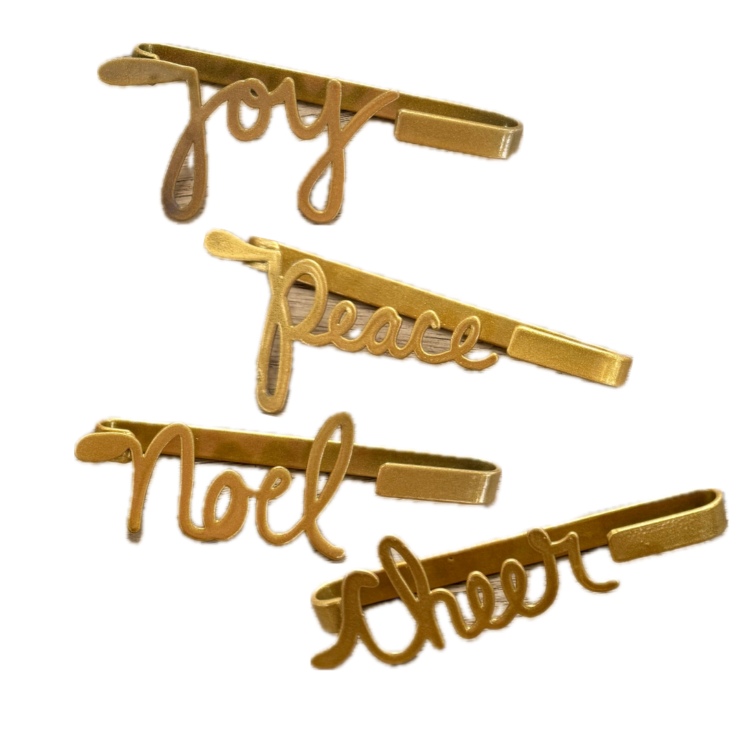 Set of gold tie bars with 'Joy', 'Peace', 'Noel', and 'Cheer' text on a white background