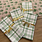 Green and white checkered towels with gold text on a wooden surface