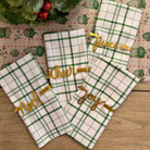 Set of green and white checkered towels with gold text on a wooden surface.