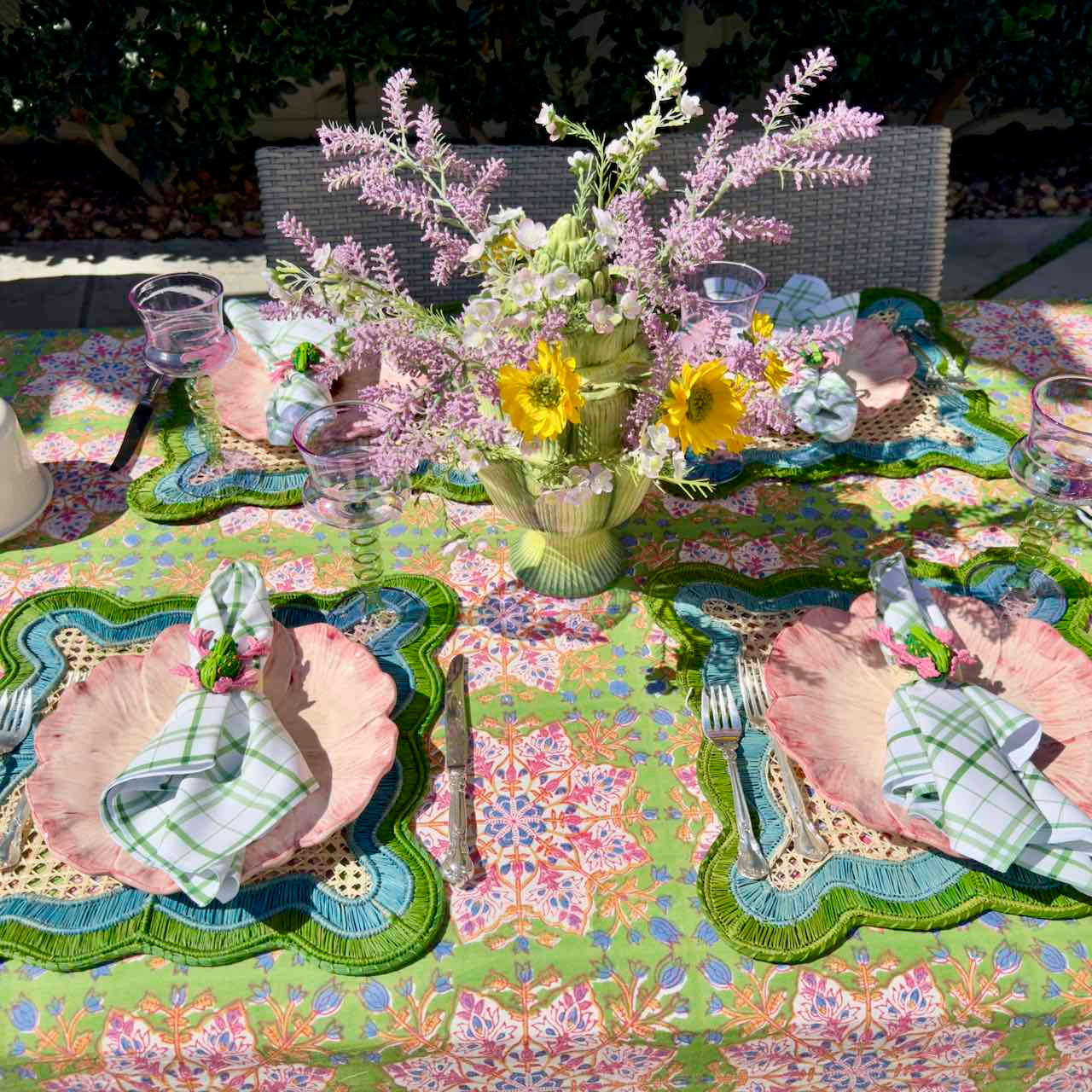 Decorative table setting with floral centerpiece and colorful tablecloth.