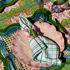 Decorative table setting with pink plates, green checkered napkins, and a colorful tablecloth.