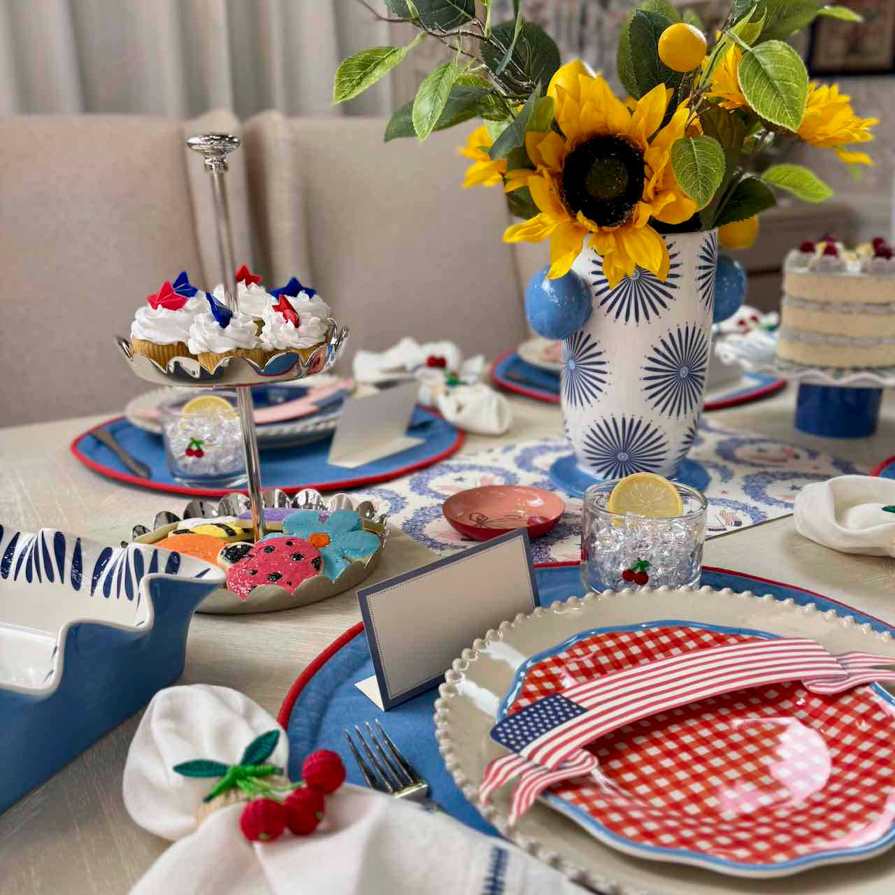 Decorative table setting with sunflowers, American-themed plates, and a cake.