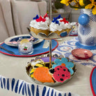 Two cupcakes with red, white, and blue decorations on a two-tiered stand with cookies on a table.