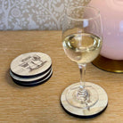 Stack of coasters with a ship design next to a glass of white wine on a coaster.