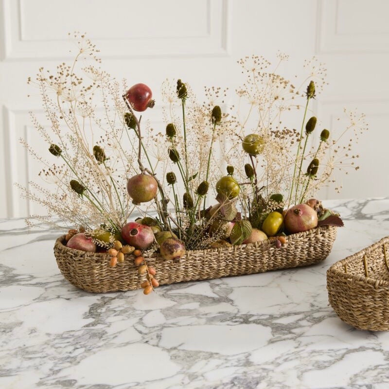 Decorative basket with pomegranates and flowers on a marble surface