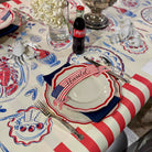 Table setting with a Coca-Cola bottle on a tablecloth featuring American flag and lobster designs.