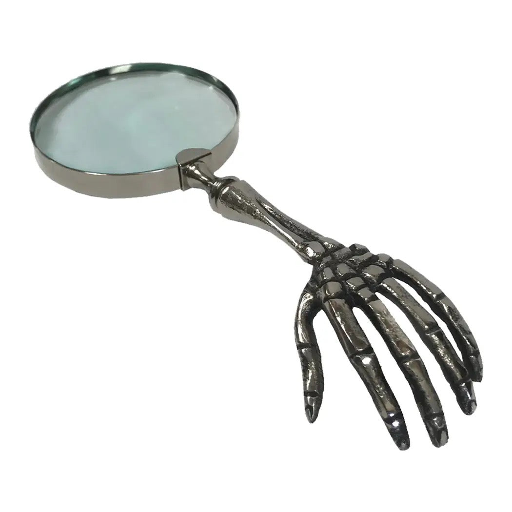A novelty magnifying glass with a metallic skeleton hand handle, shown on a plain white background.