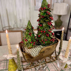 Decorative Christmas scene with trees in a sleigh, candles, and plaid fabric on a table.