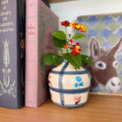 Decorative vase with flowers on a shelf next to books and a picture of a donkey.
