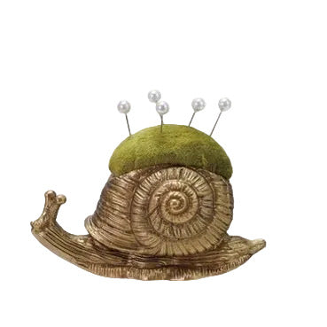 Snail-shaped pincushion with green top and pearl pins on a white background