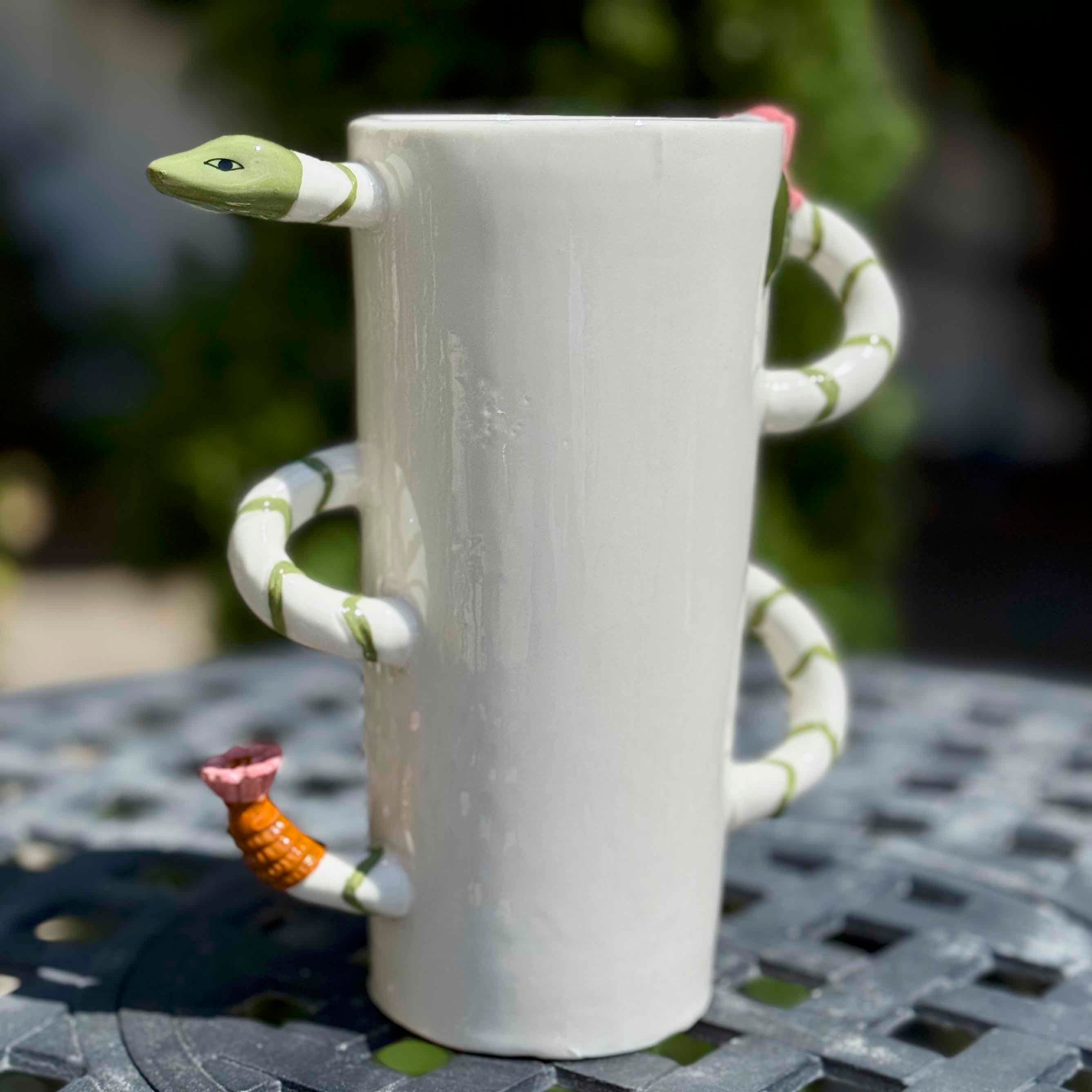 White mug with a snake design on a table outdoors