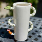 White mug with snake handle on a textured surface