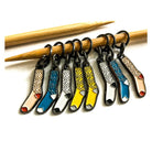 Colorful knitting needle markers with various patterns on a white background