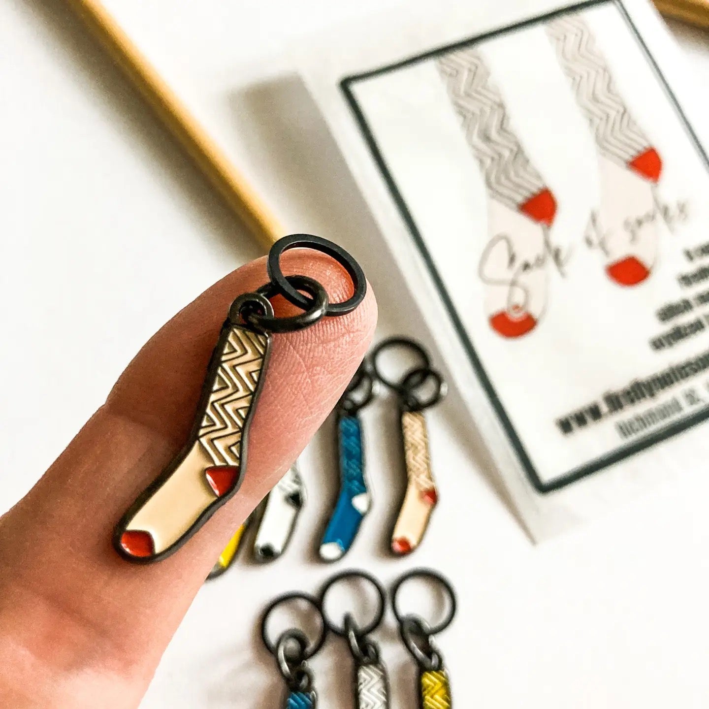 Hand holding a keychain with more keychains and a card in the background
