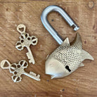Fish-shaped brass lock with two keys on a wooden surface
