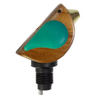 Wooden bird-shaped object with a green body and gold beak on a white background